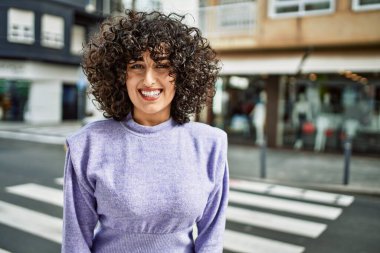 Orta Doğu 'lu genç bir kadın sokakta kendinden emin gülümsüyor.
