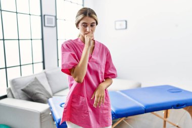 Evde fizyoterapist olarak çalışan genç sarışın kadın kendini iyi hissetmiyor ve soğuk algınlığı veya bronşitin belirtisi olarak öksürüyor. sağlık hizmeti kavramı. 