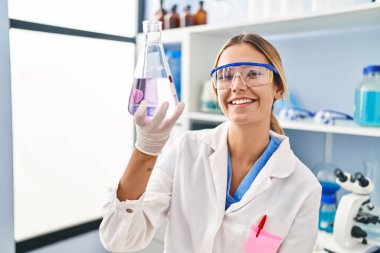 Laboratuvarda sıvıyı ölçen genç İspanyol bilim kadını.