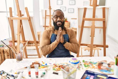 Afro-Amerikalı bir sanatçı sanat stüdyosunda el ele dua ediyor ve af diliyor.. 