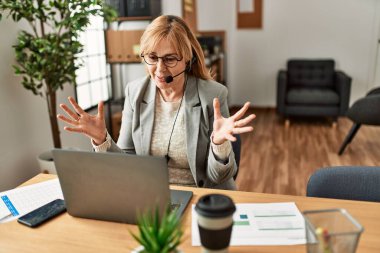Orta yaş çağrı merkezi ajanının ofisteki bilgisayarı kullanarak görüntülü arama yapması..