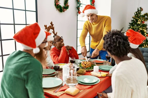 一群年轻人笑着高兴地吃着圣诞大餐 男人切烤火鸡在家吃 — 图库照片