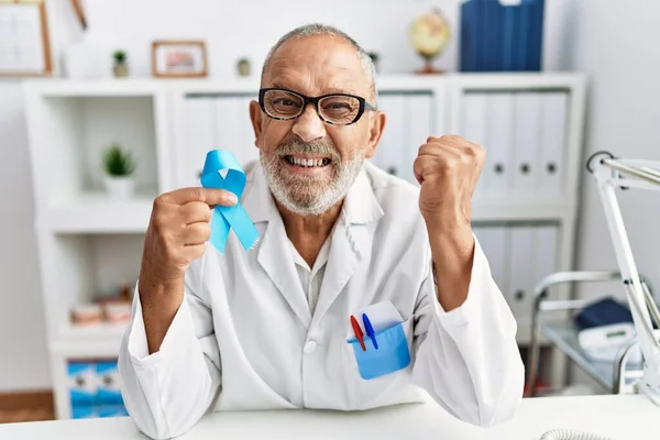 Mature Doctor Man Holding Blue Ribbon Clinic Screaming Proud Celebrating — Stok fotoğraf