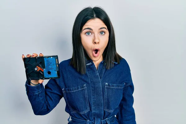 Young Brunette Woman Holding Hdd Disk Scared Amazed Open Mouth — 스톡 사진