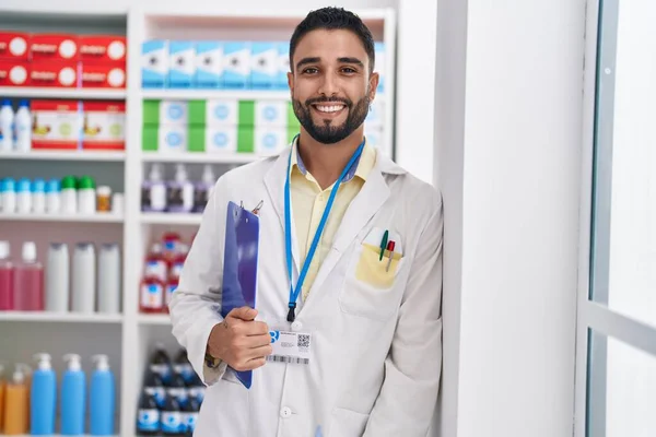 Jovem Árabe Homem Farmacêutico Sorrindo Confiante Segurando Prancheta Farmácia — Fotografia de Stock