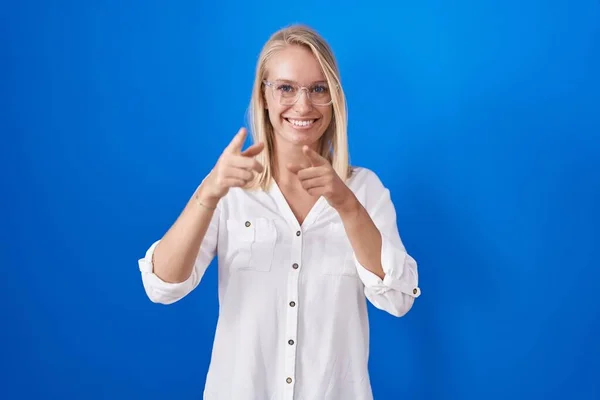 Mladá Běloška Stojí Nad Modrým Pozadím Ukazuje Prstem Kameru Šťastnou — Stock fotografie