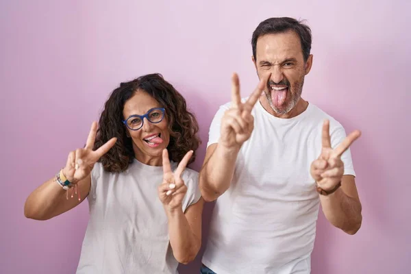 Middle Age Hispanic Couple Together Pink Background Smiling Tongue Out — 图库照片