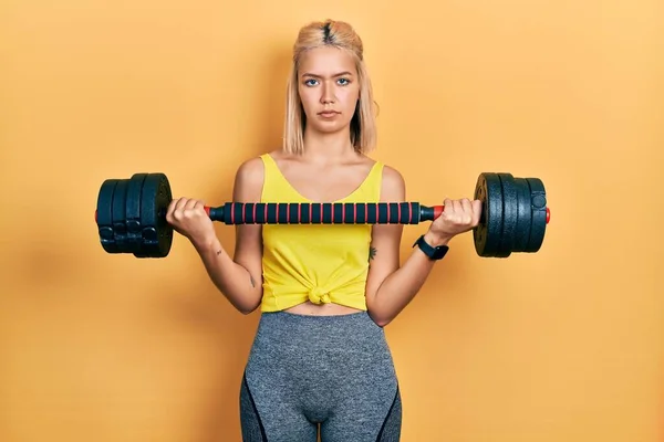Beautiful Blonde Woman Wearing Sportswear Using Dumbbells Relaxed Serious Expression — Zdjęcie stockowe