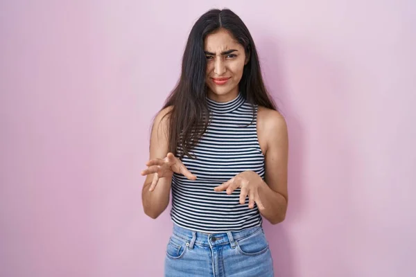 Young teenager girl wearing casual striped t shirt disgusted expression, displeased and fearful doing disgust face because aversion reaction. with hands raised