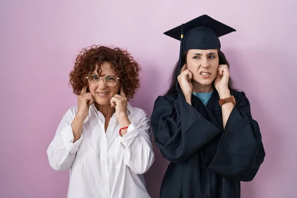 Hispanic Mother Daughter Wearing Graduation Cap Ceremony Robe Covering Ears — ストック写真