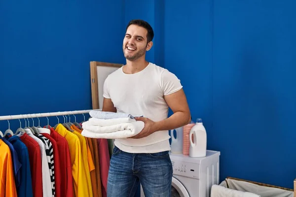 Çamaşır Odasında Katlanmış Temiz Havluları Tutan Genç Spanyol Adam Kameraya — Stok fotoğraf