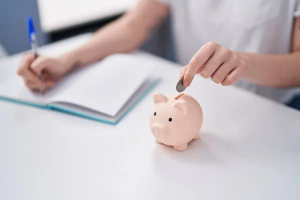 Young Woman Writing Notebook Inserting Coin Piggy Bank Home — 스톡 사진