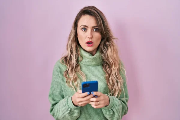 Young Caucasian Woman Using Smartphone Typing Message Shock Face Looking — Fotografia de Stock