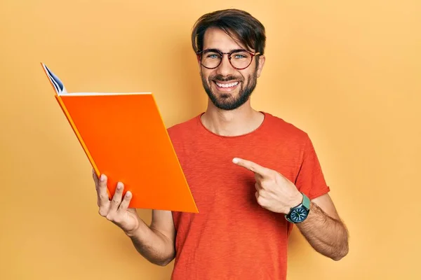 Jovem Hispânico Homem Ler Livro Sorrindo Feliz Apontando Com Mão — Fotografia de Stock