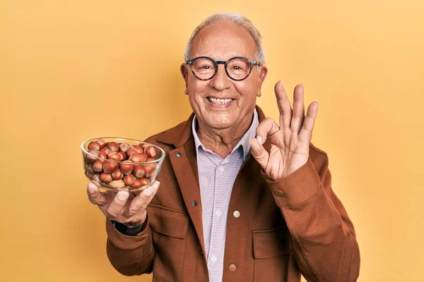 Senior Man Grey Hair Holding Hazelnuts Doing Sign Fingers Smiling — Fotografia de Stock