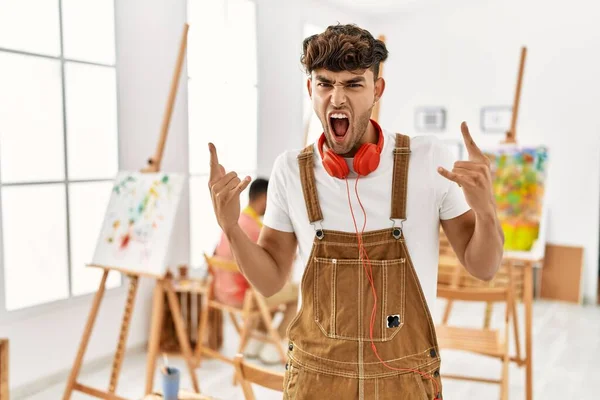 Young Hispanic Man Art Studio Shouting Crazy Expression Doing Rock — Stockfoto