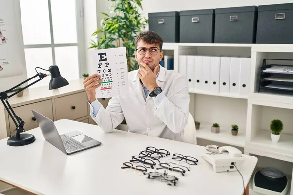 Jonge Spaanse Man Werkt Bij Oogheelkunde Kliniek Serieus Gezicht Denken — Stockfoto