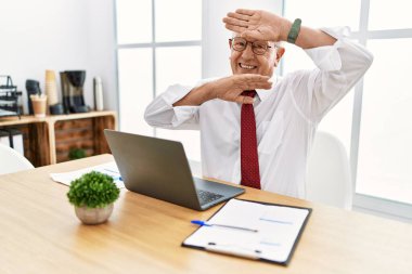 Ofiste çalışan kıdemli bir adam bilgisayarda gülümseyen bir dizüstü bilgisayar kullanıyor. Şaşırdım ve çıktım. 