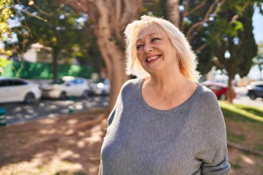 Parkta kendine güvenen orta yaşlı sarışın bir kadın.