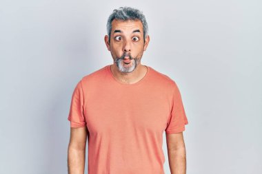 Gri saçlı, sıradan tişörtlü yakışıklı orta yaşlı bir adam dudaklı balık suratlı, çılgın ve komik bir jest yapıyor. Komik ifade. 