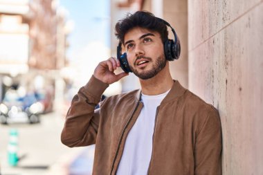 Sokakta müzik dinlerken kendinden emin gülümseyen İspanyol genç adam.