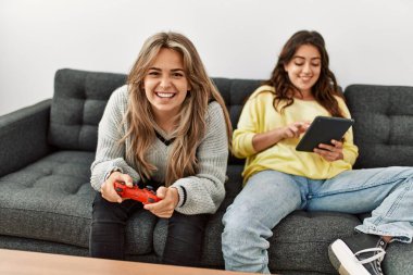 Gülümseyen genç çift video oyunu oynayıp evde touchpad kullanıyor..