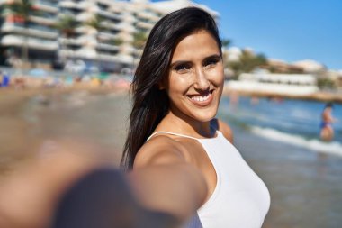 Genç İspanyol kadın gülümsüyor. Sahilde özgüven selfie çekiyor.