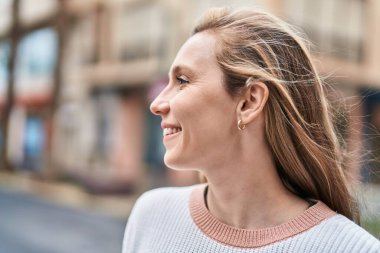 Young blonde woman smiling confident looking to the side at street