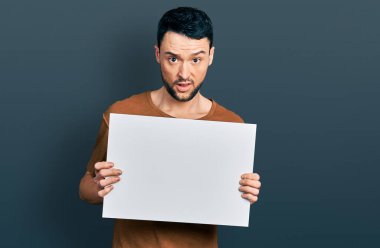 Sakallı, boş pankartı olan İspanyol bir adam. Şok olmuş suratına. Şüpheci ve alaycı bakıyor. 