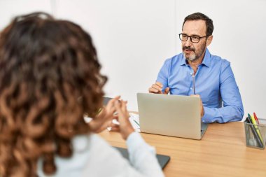 İki orta yaşlı iş adamı ofiste konuşurken gülümsüyor..