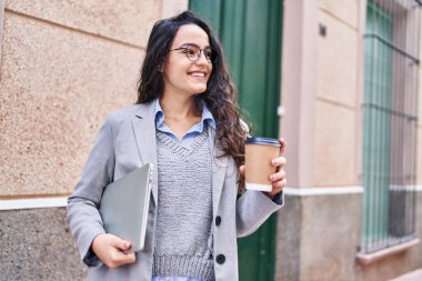 Sokakta dizüstü bilgisayar içen Latin kökenli genç bir yönetici.