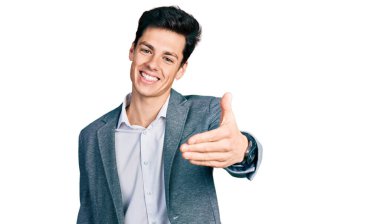 İş kıyafetleri giymiş genç İspanyol bir adam gülümseyerek selamlama ve hoş geldin demek için tokalaşmayı teklif ediyor. başarılı iş. 