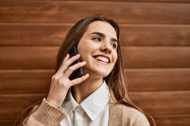 Genç İspanyol iş kadını gülümsüyor. Şehirdeki akıllı telefondan mutlu bir şekilde konuşuyor..