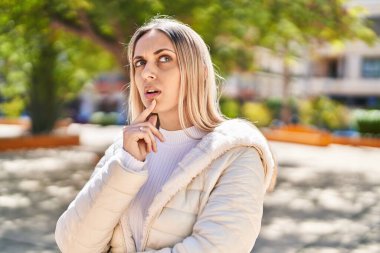 Parkta şüpheli bir ifadeyle duran genç kadın.