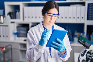 Young woman scientist using touchpad at laboratory