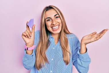 Makyaj süngeri tutan güzel İspanyol kadın zaferi mutlu bir gülümsemeyle ve kazanan yüz ifadesiyle kutluyor. 