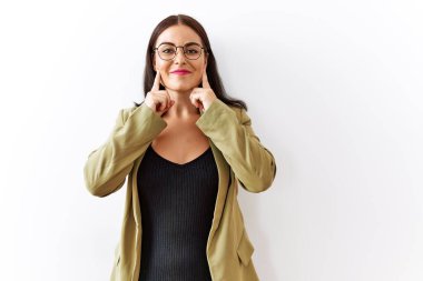 Young brunette woman standing over isolated background smiling with open mouth, fingers pointing and forcing cheerful smile 
