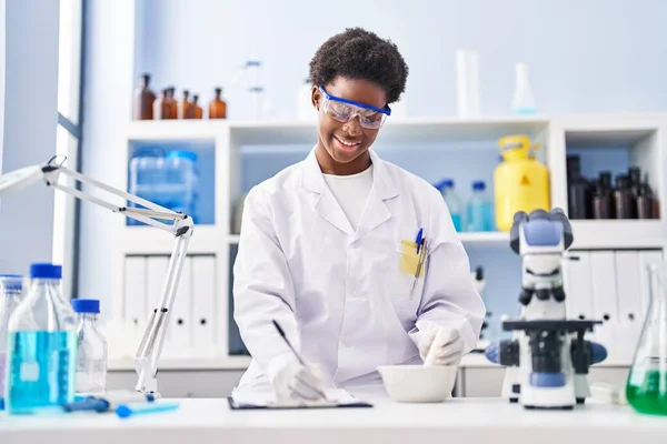 Mujer Afroamericana Vistiendo Uniforme Científico Escribir Portapapeles Trabajando Laboratorio —  Fotos de Stock