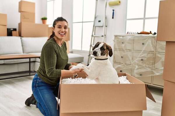 Молодая женщина улыбается уверенно играя с собакой дома