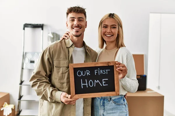 Young Caucasian Couple Smiling Happy Holding Blackboard Our First Home — Stock Photo, Image