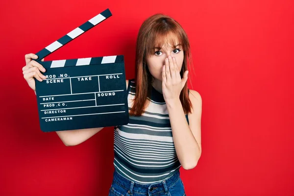 Roodharige Jonge Vrouw Met Videofilm Klapbord Mond Met Hand Geschokt — Stockfoto