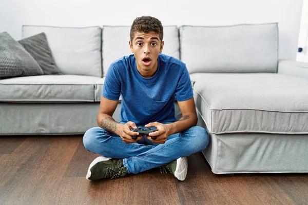 Jovem Homem Hispânico Bonito Jogando Videogame Sentado Junto Sofá Assustado — Fotografia de Stock