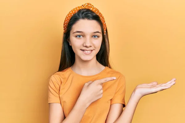 Молодая Брюнетка Повседневной Оранжевой Футболке Удивлена Улыбается Камеру Представляя Рукой — стоковое фото