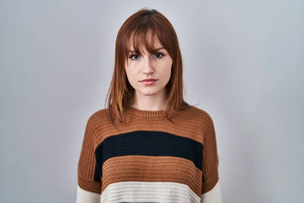 年轻美丽的女人穿着条纹毛衣在孤立的背景上放松 脸上带着严肃的表情 简单而自然地看着相机 — 图库照片
