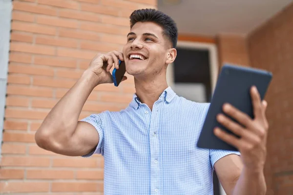 Young Hispanic Man Talking Smartphone Using Touchpad Street — Zdjęcie stockowe