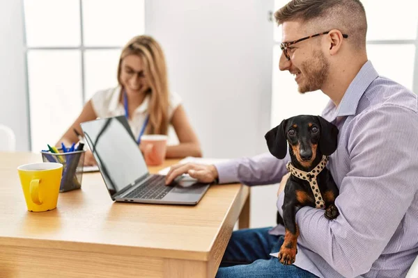 Two business workers smiling happy working with dog at the office.
