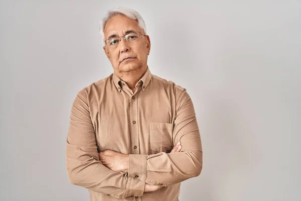 Hispanic senior man wearing glasses skeptic and nervous, disapproving expression on face with crossed arms. negative person.