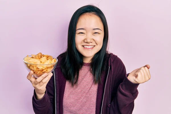 Young Chinese Girl Holding Potato Chip Screaming Proud Celebrating Victory — Foto de Stock