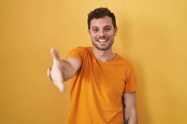 Homem Hispânico Jovem Sobre Fundo Amarelo Sorrindo Amigável Oferecendo Aperto — Fotografia de Stock