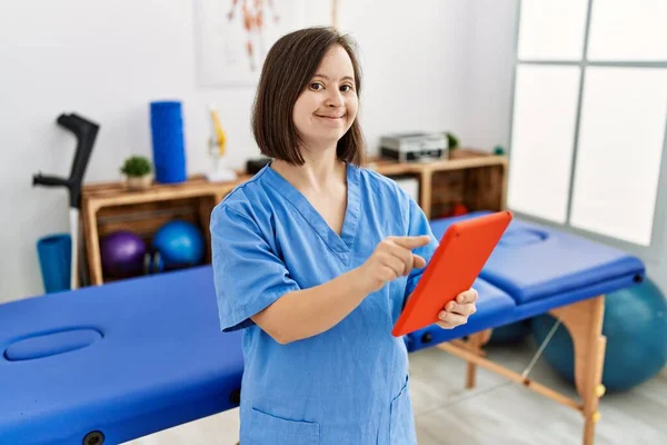 ダウン症候群を持つブルネットの女性は理学療法クリニックでタブレットを使用して作業 — ストック写真
